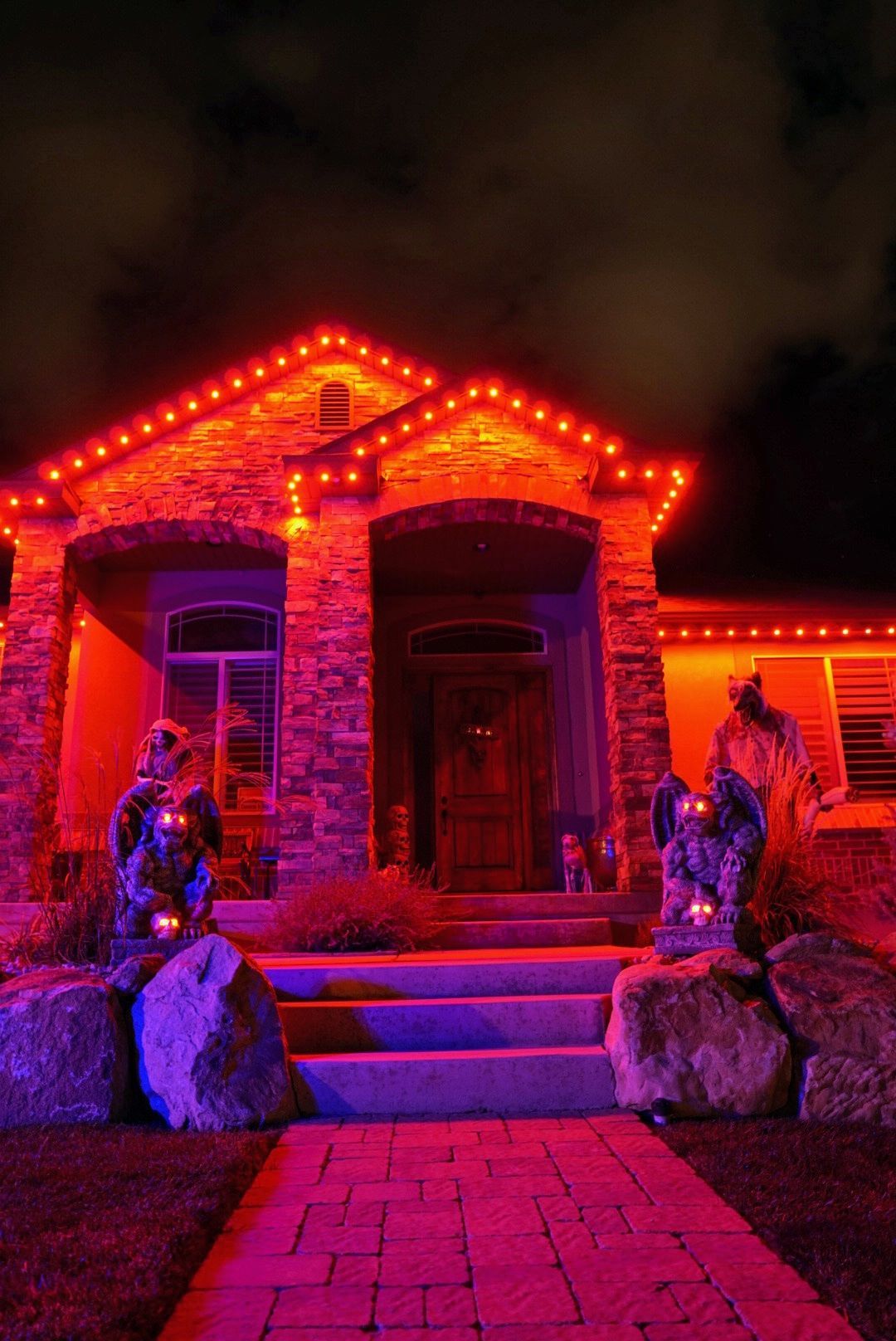 A house is decorated for halloween with red and purple lights.