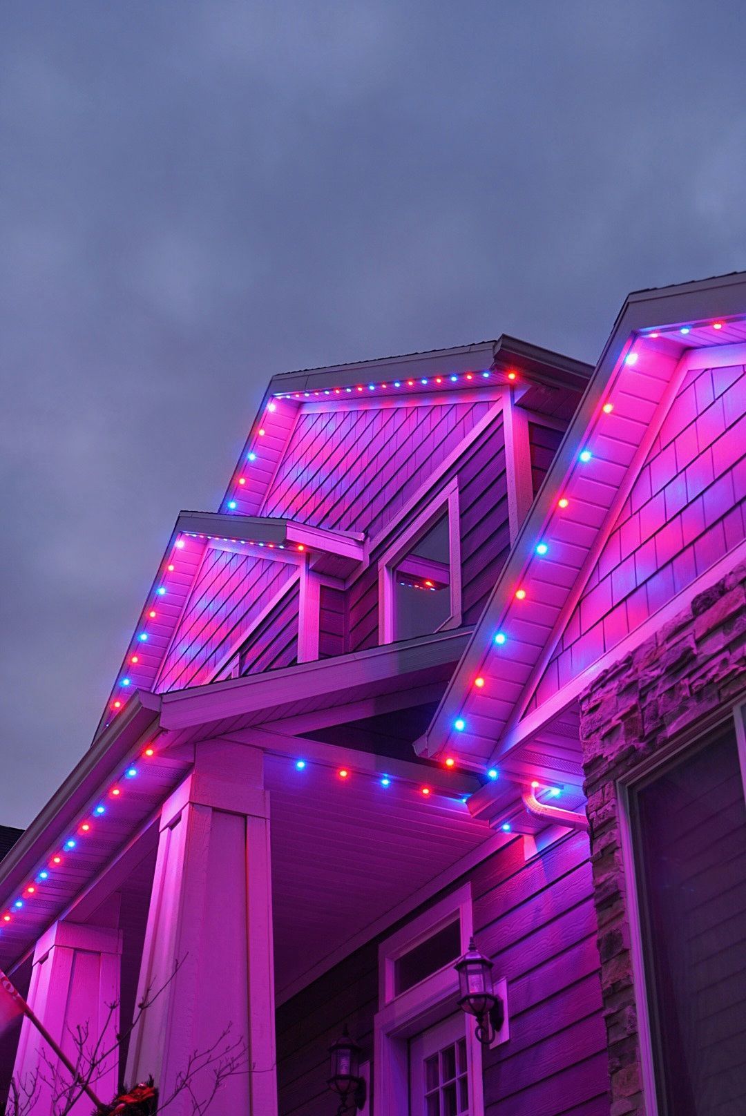 A house with purple and blue christmas lights on the roof.