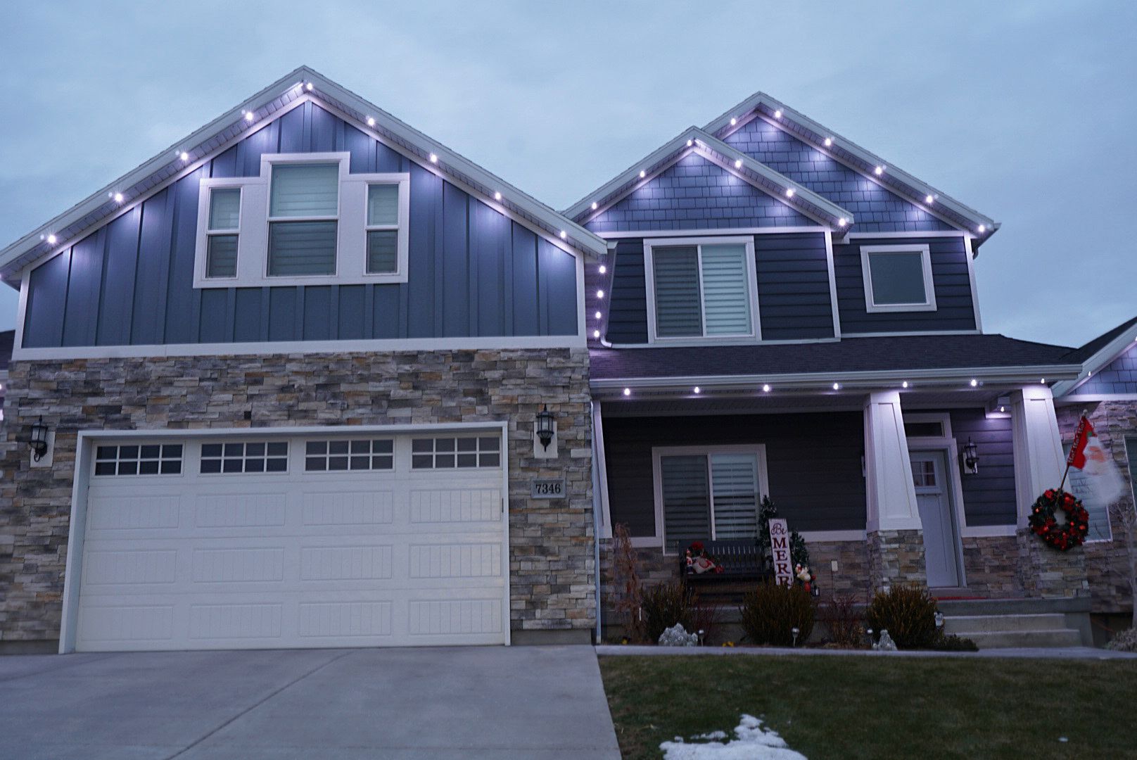 A large house is decorated with christmas lights and a wreath.
