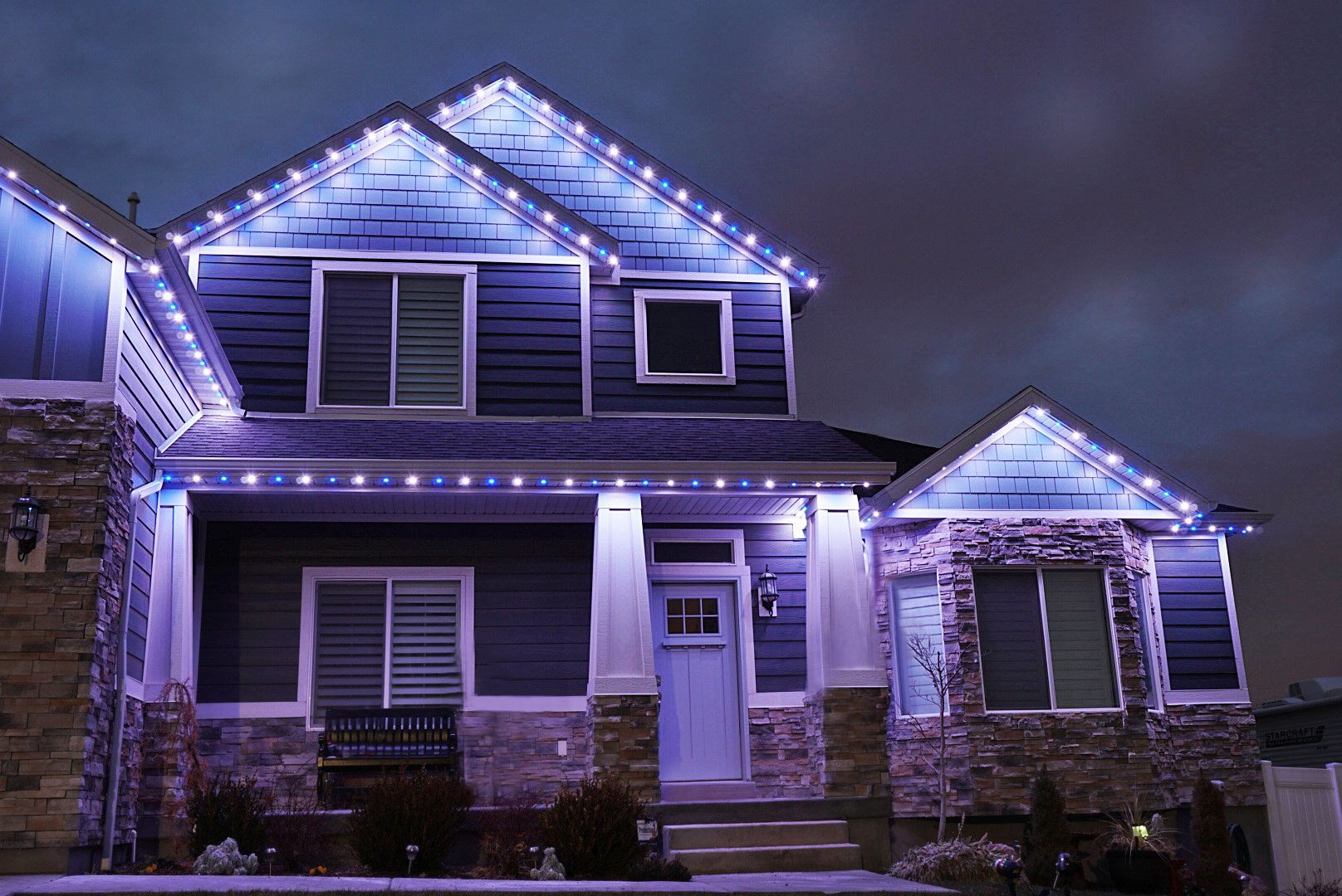 A blue house with purple lights on it is lit up at night.