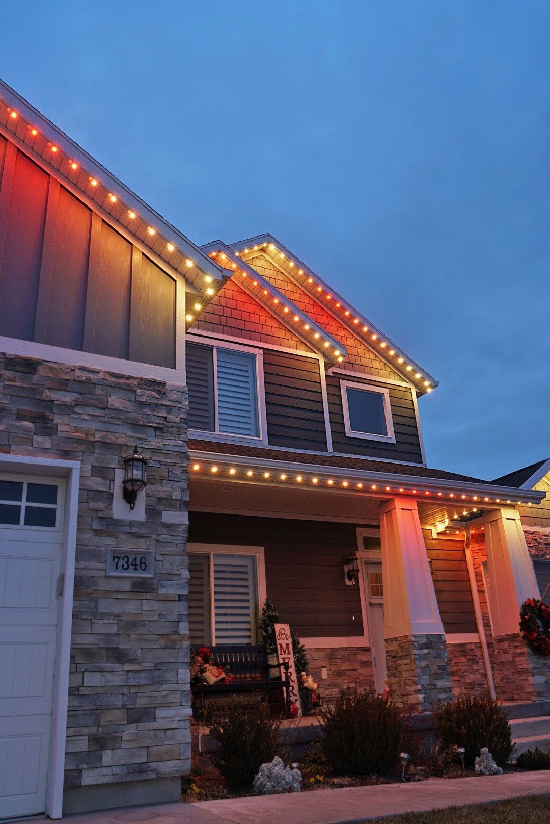 A house with christmas lights on the roof is lit up at night.