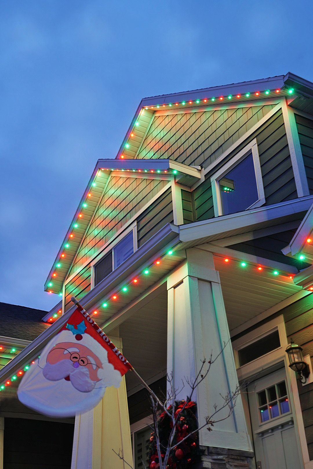 A house is decorated with christmas lights and a santa flag.