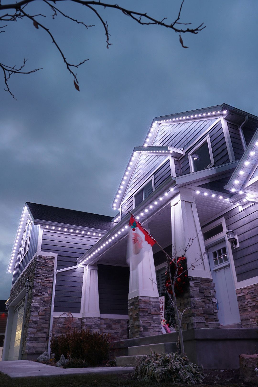 A house is decorated with christmas lights and a person is standing on the porch.