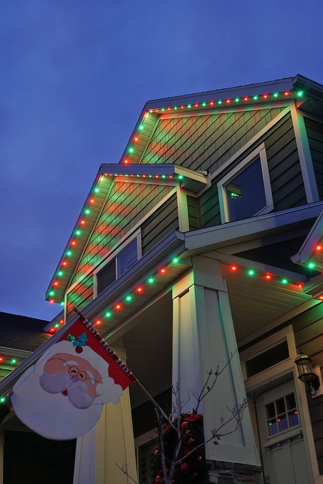A house is decorated with christmas lights and a santa flag.