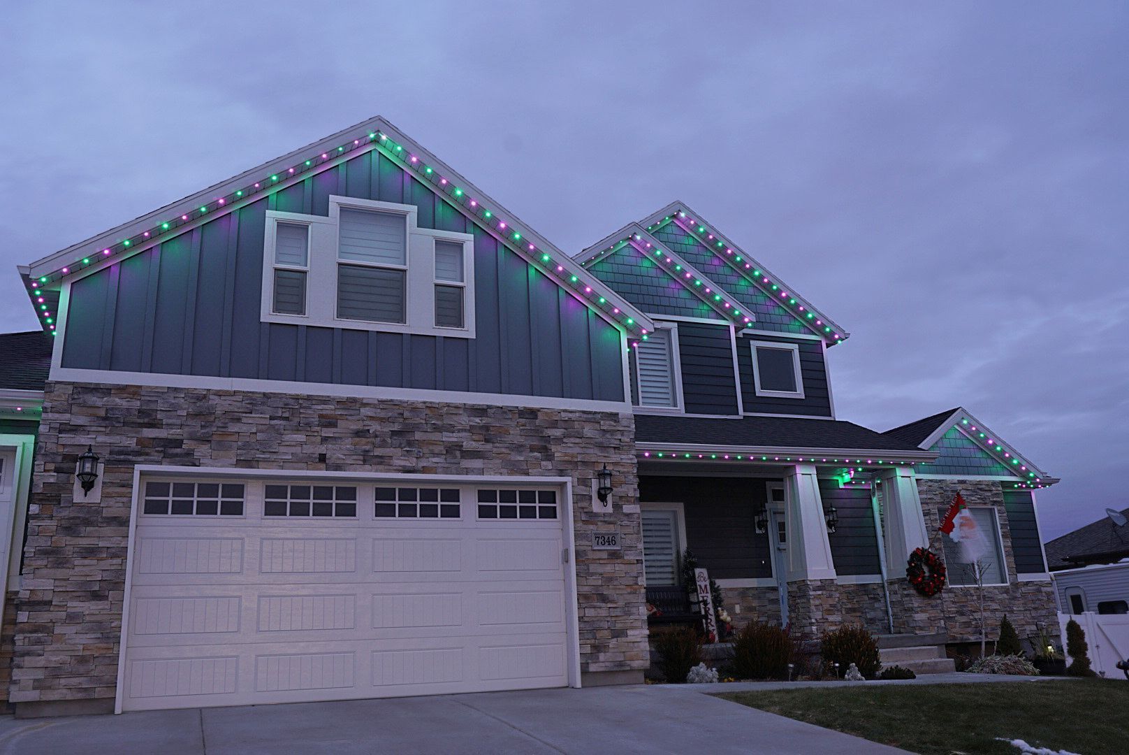 The house is decorated with christmas lights and has a white garage door.