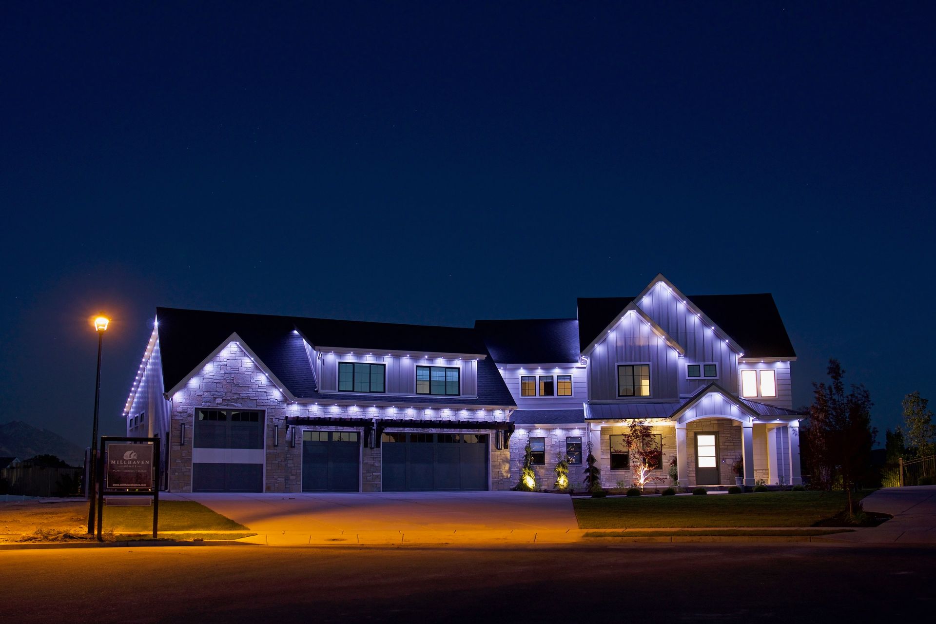A large house with christmas lights on it is lit up at night.