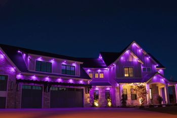 A large house is lit up with purple lights at night.