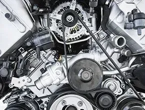 Close-up of a car engine showing belts, pulleys, and various mechanical components.