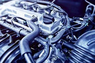 Close-up of a car engine with various black hoses, wires, and a silver engine block.