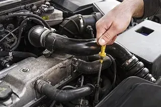 Person checking car engine oil with a dipstick.