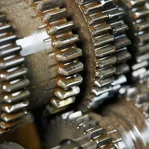 Close-up of interlocking metal gears, covered in oil, suggesting a mechanical system in operation.