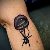 A tattoo of a spider and lips on a person 's arm.