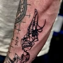 A man has a tattoo of a woman hanging upside down on his forearm.