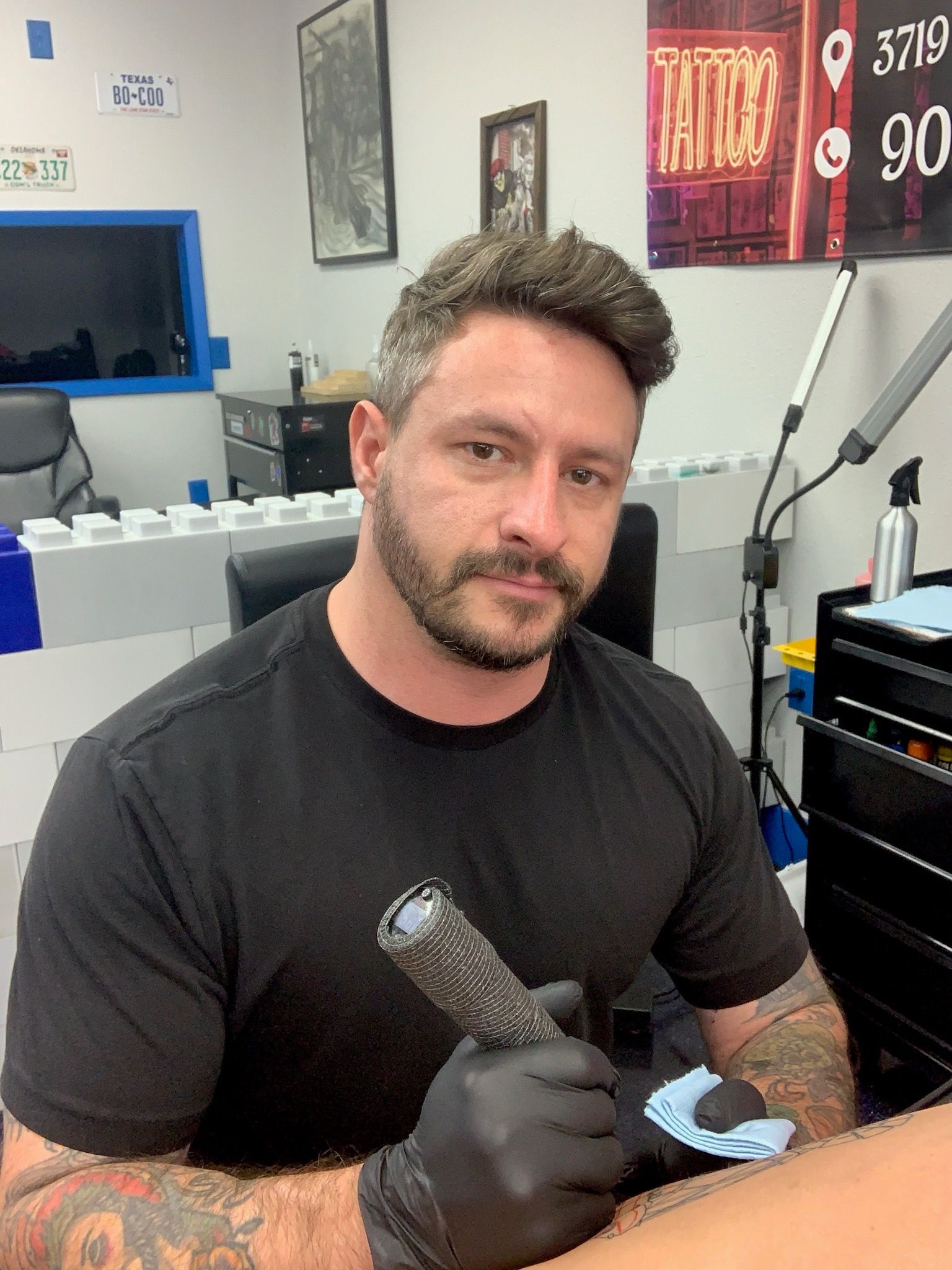A man is getting a tattoo on another man 's arm.
