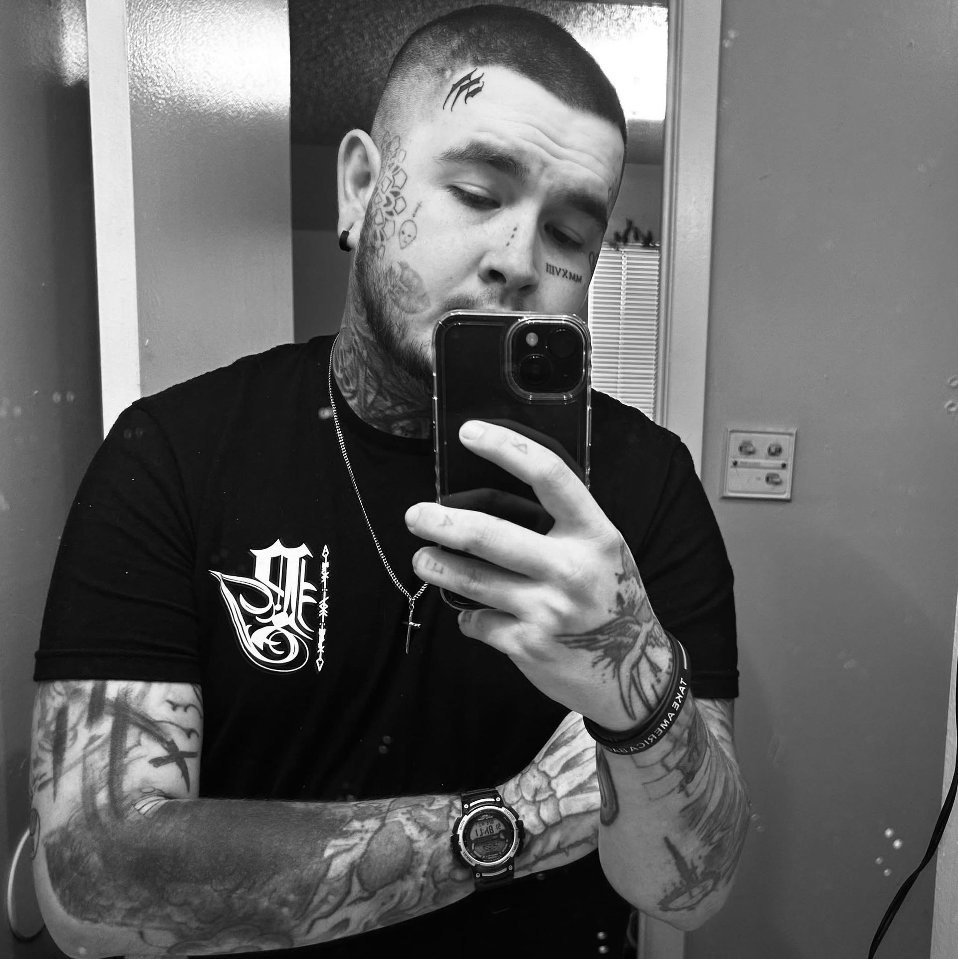 A man with tattoos is taking a selfie with his phone
