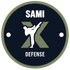 Abzeichen für SAMI Defense: Schwarzer Kreis mit tretender weisser Figur, grünem „X“ und Text „SAMI DEFENSE“.