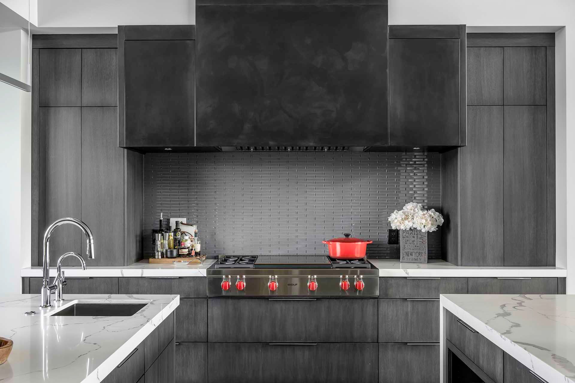 A kitchen with a stove , sink , and hood.