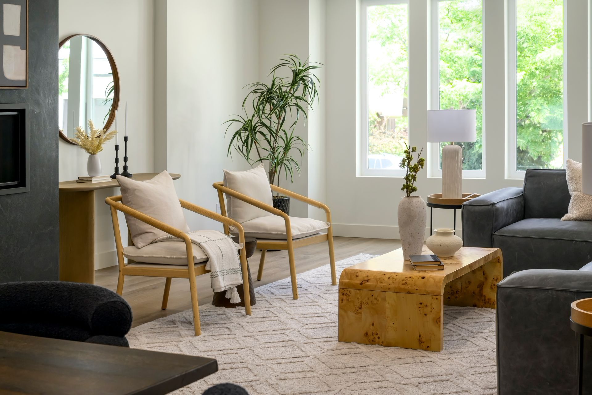 Living room with two wooden chairs, a sofa, coffee table, rug, and large windows.