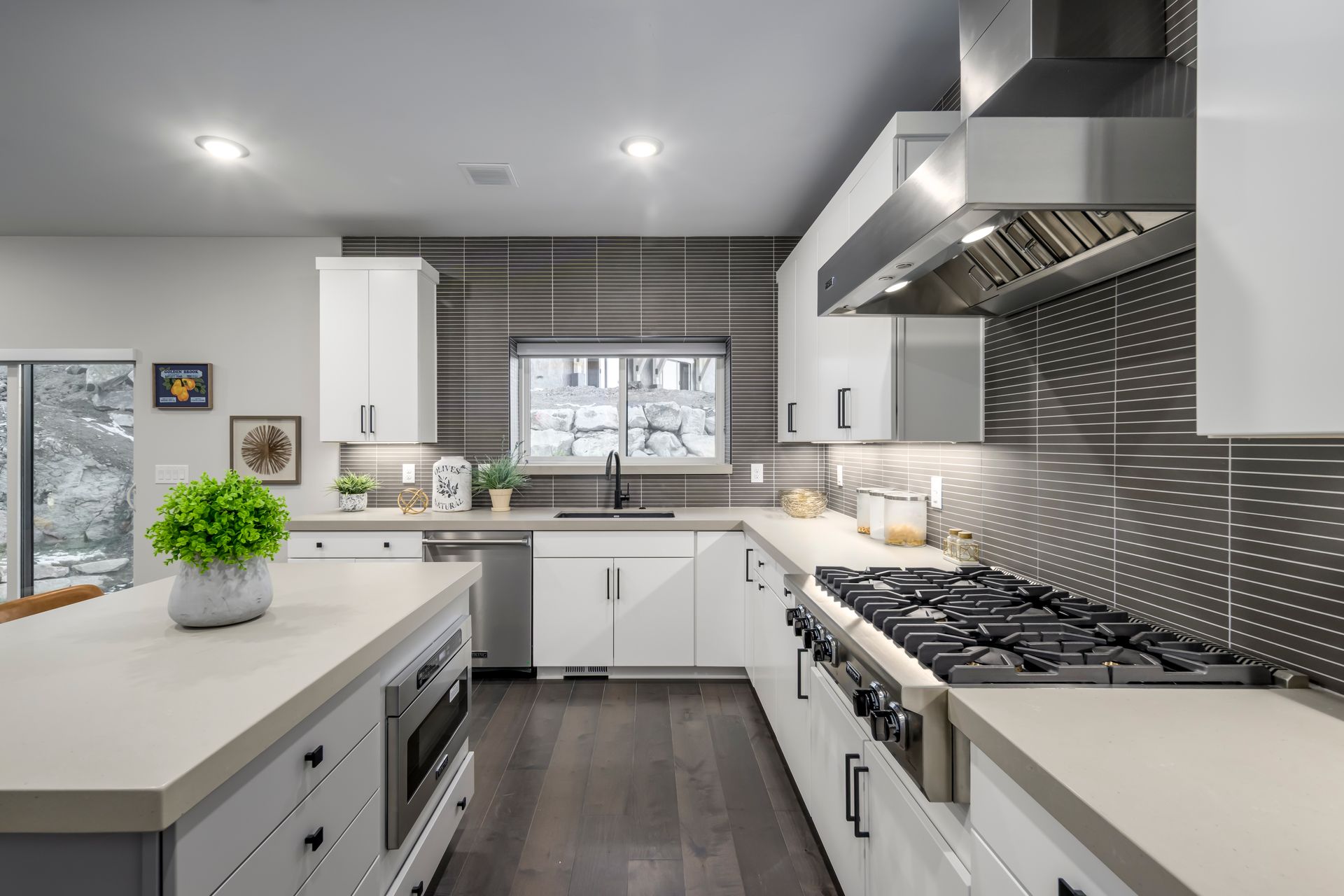 Modern kitchen with white cabinets, stainless steel appliances, dark wood floors, and island.