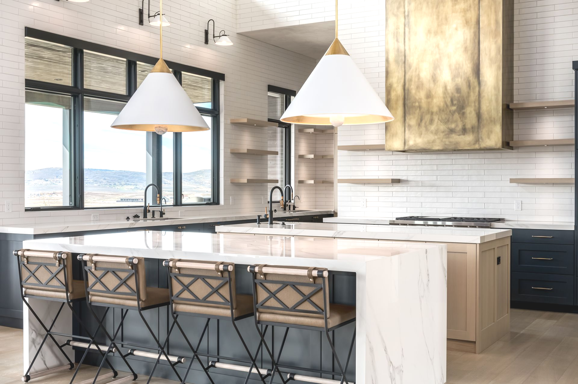 Modern kitchen with island, pendant lights, and bar stools. White, gold, and dark blue color scheme.