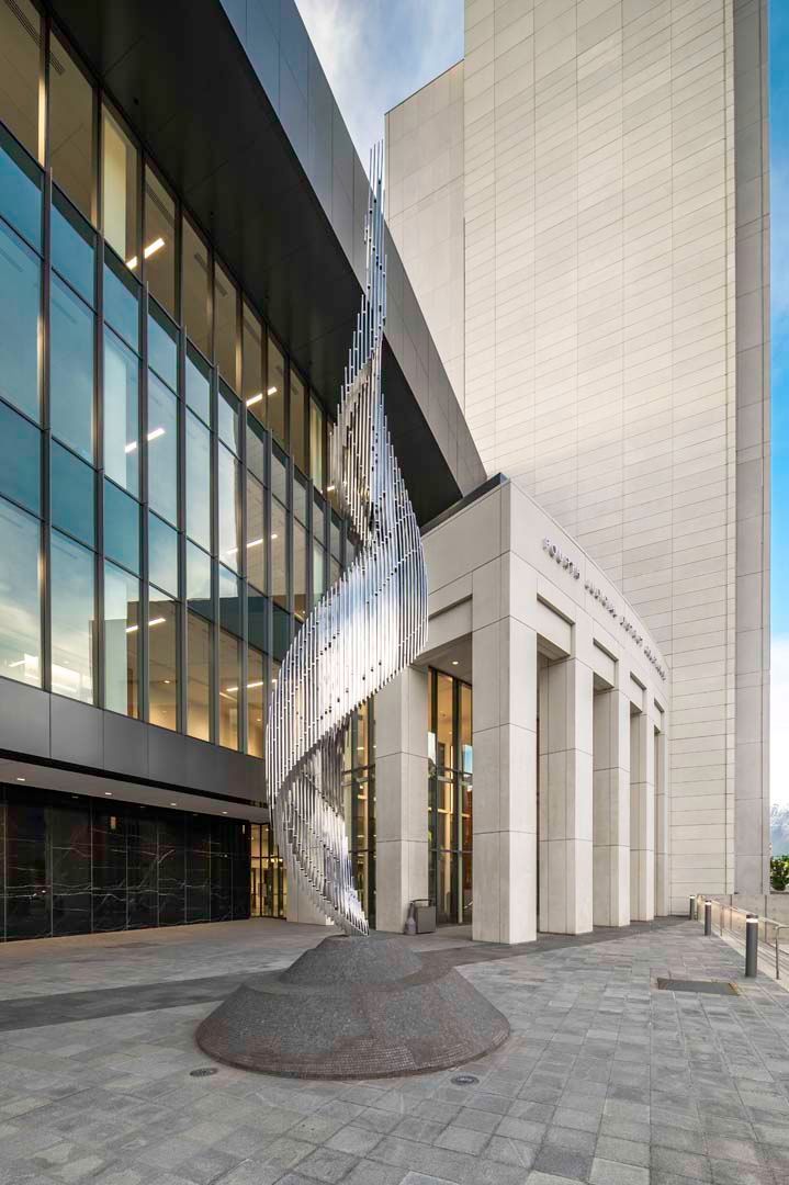 A modern building entrance with a polished metal sculpture and cobblestone path.