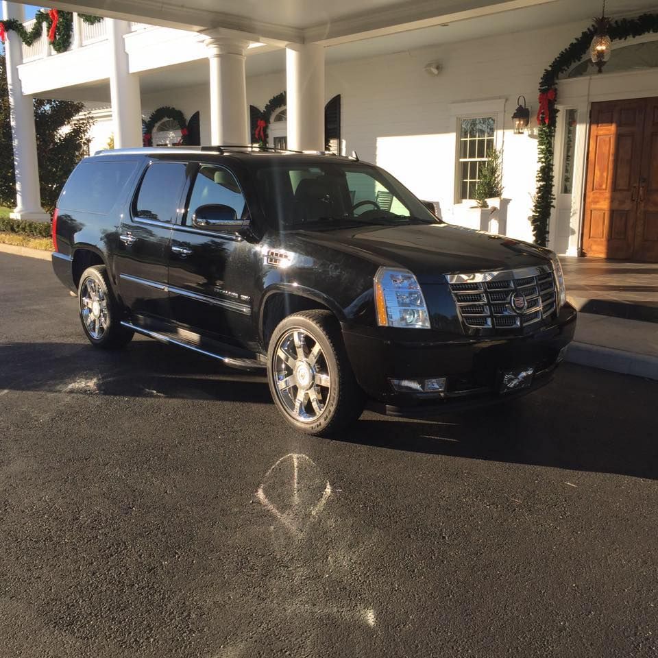 A black suv is parked in front of a white building