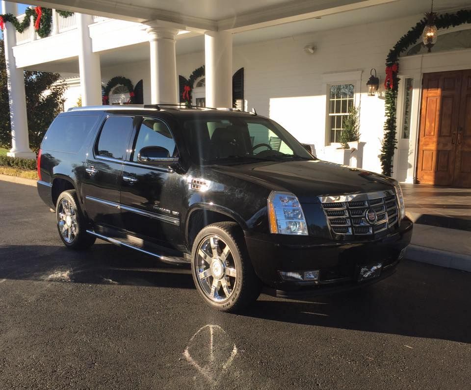 A black suv is parked in front of a white house