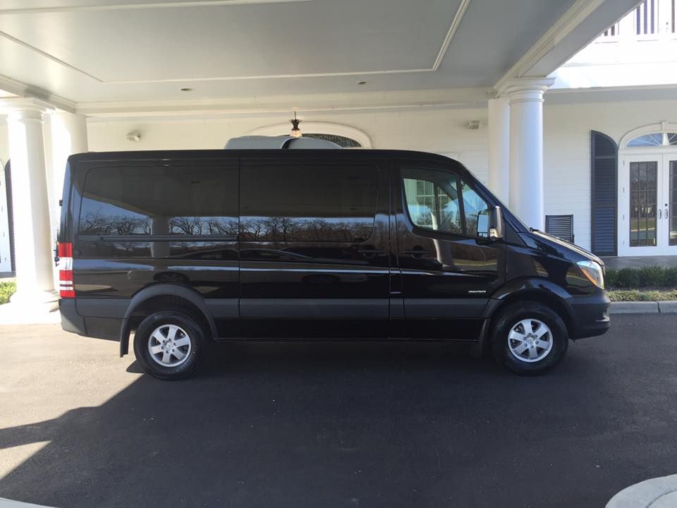 A black van is parked in front of a white building.