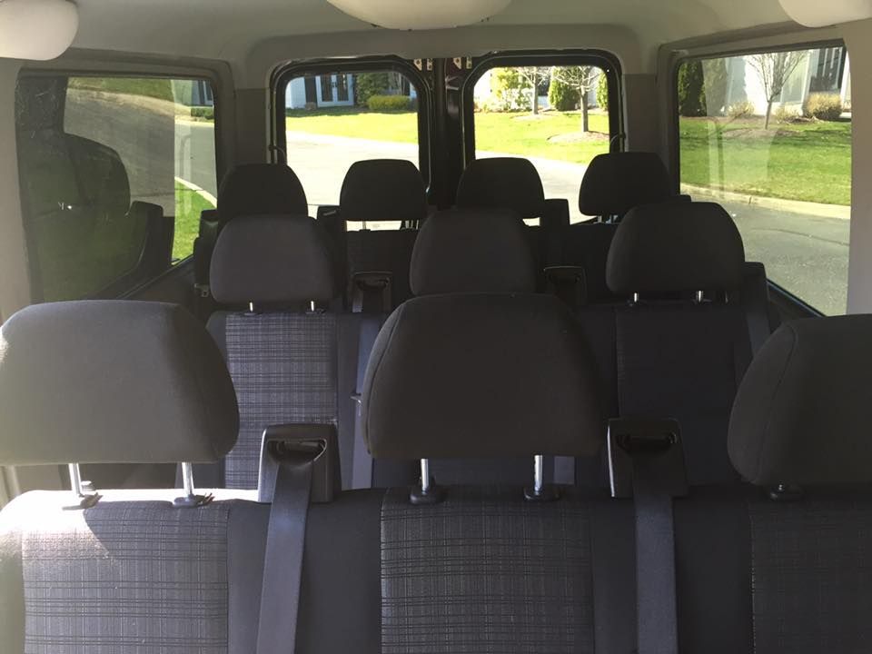 The back seat of a van with a lot of seats and a lot of windows.