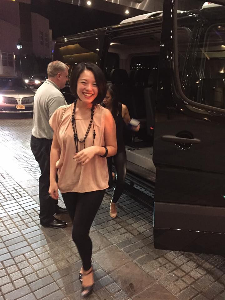 A woman is standing in front of a black van.