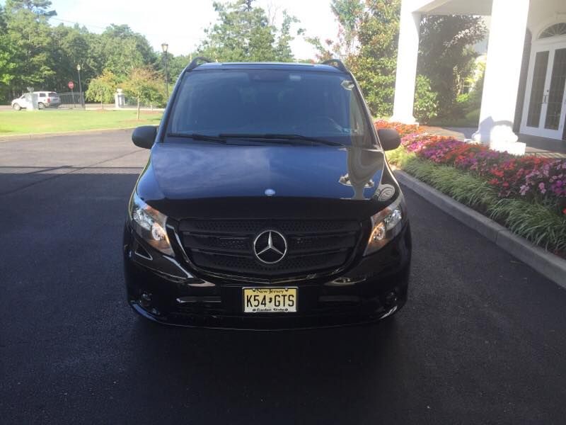A black mercedes van is parked in front of a house.