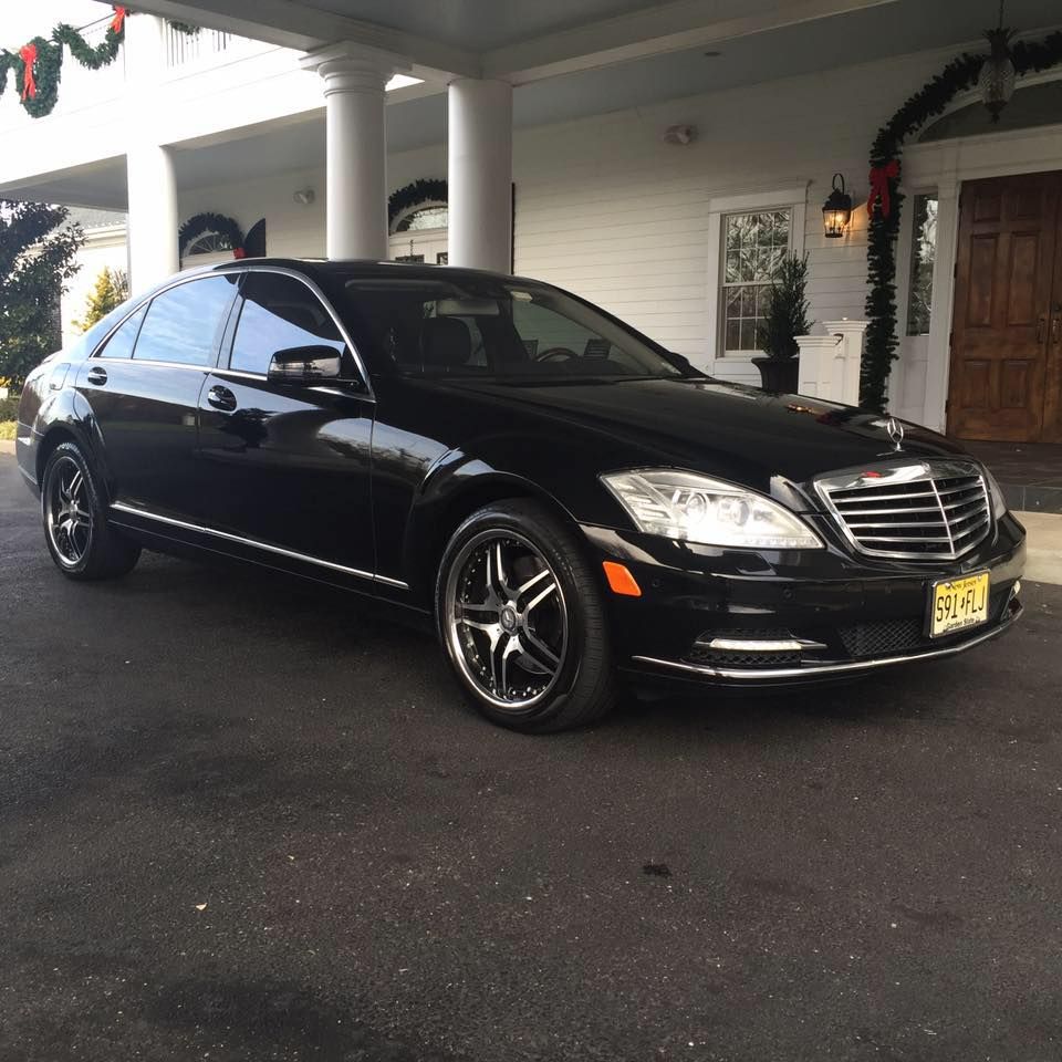 A black car is parked in front of a white house