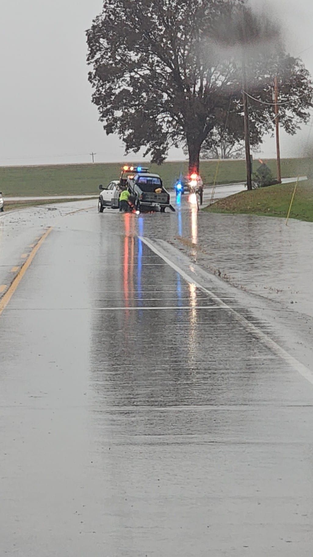A police car is parked on the side of a flooded road.