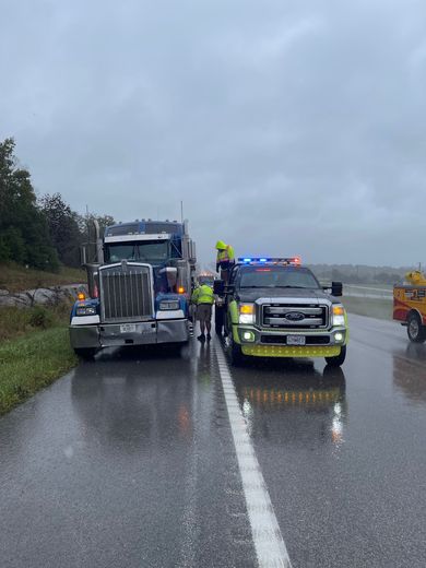 A truck is being towed by a tow truck on a wet road.