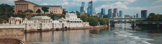 Philadelphia skyline viewed from the Schuylkill River, showing the Art Museum, Boathouse Row, and city skyscrapers.