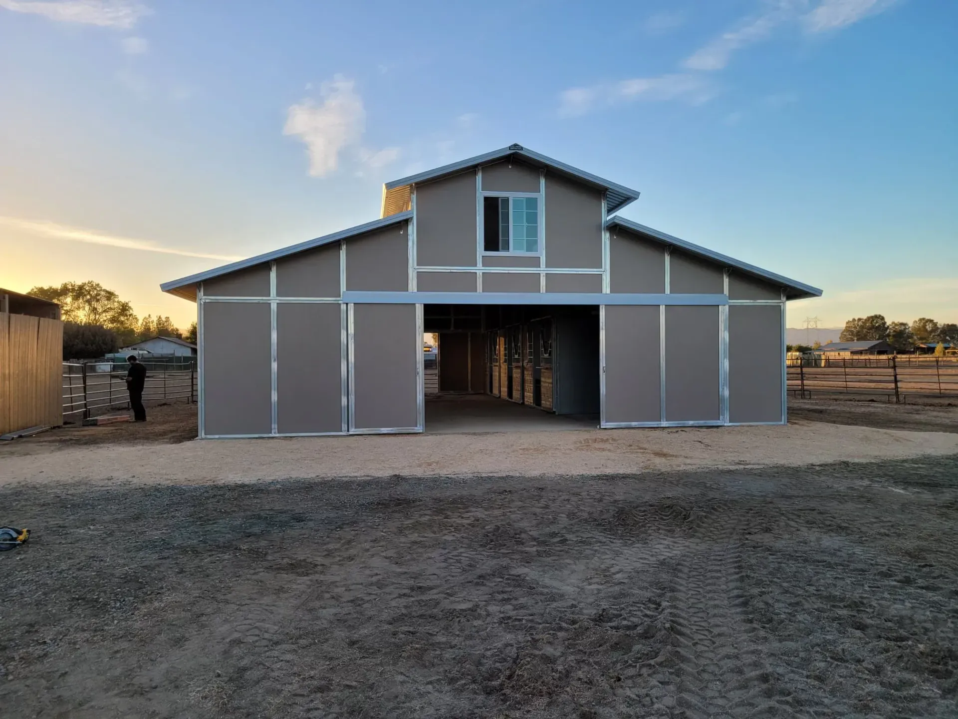A large barn is sitting in the middle of a dirt field.