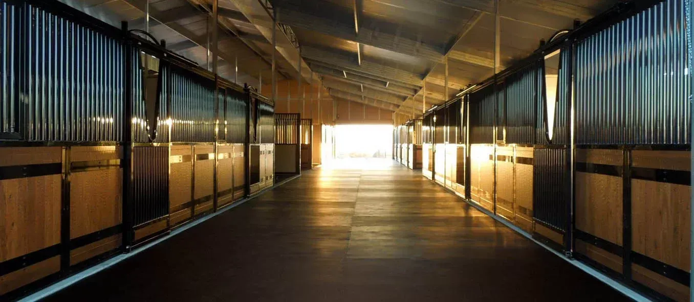 A long hallway filled with rows of wooden stables.