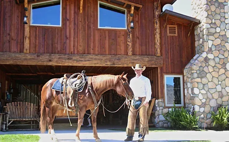 A man standing next to a horse in front of a house