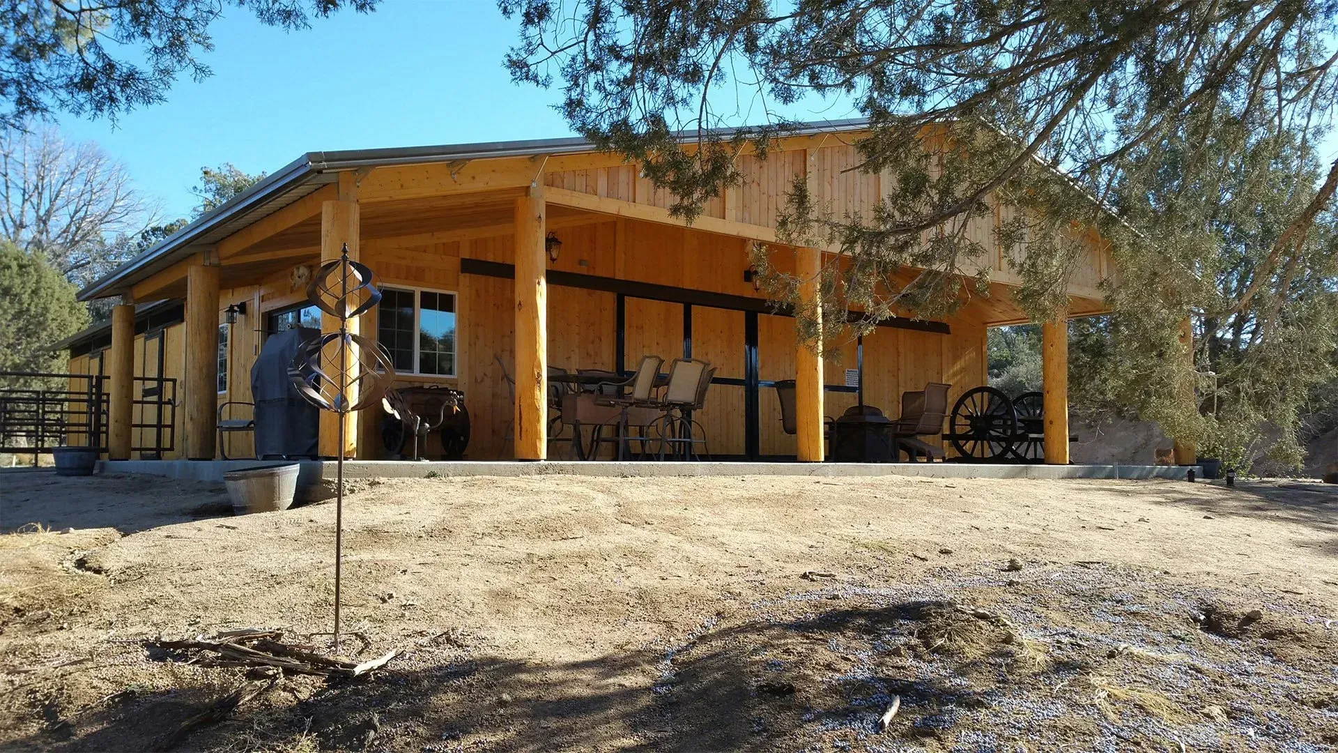 A wooden house with a porch and chairs in the middle of a field.