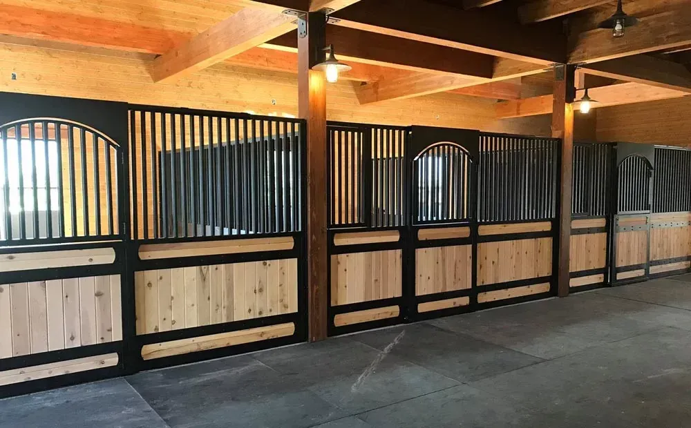 A row of wooden horse stalls in a barn.