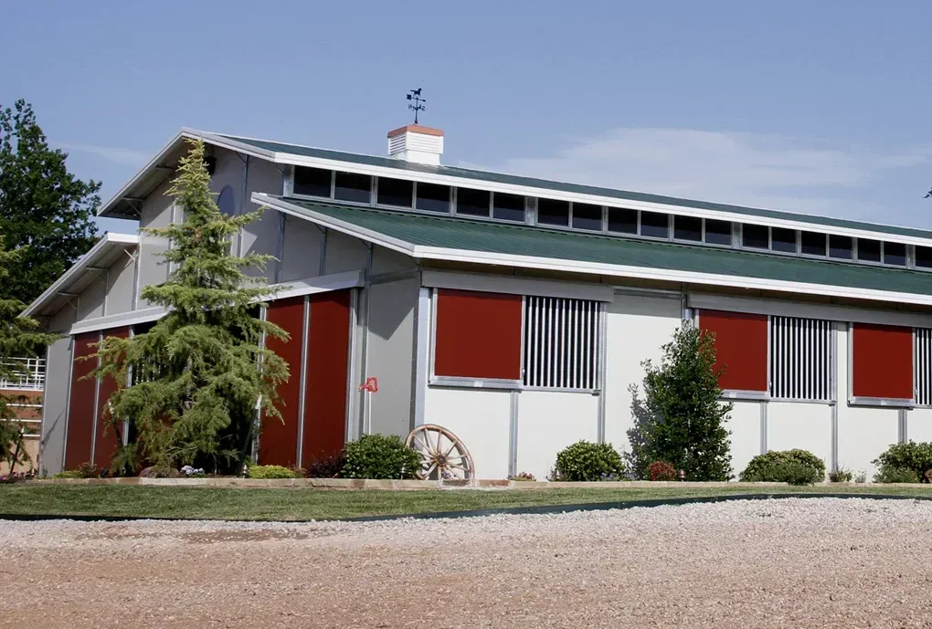 A barn with a green roof and red doors