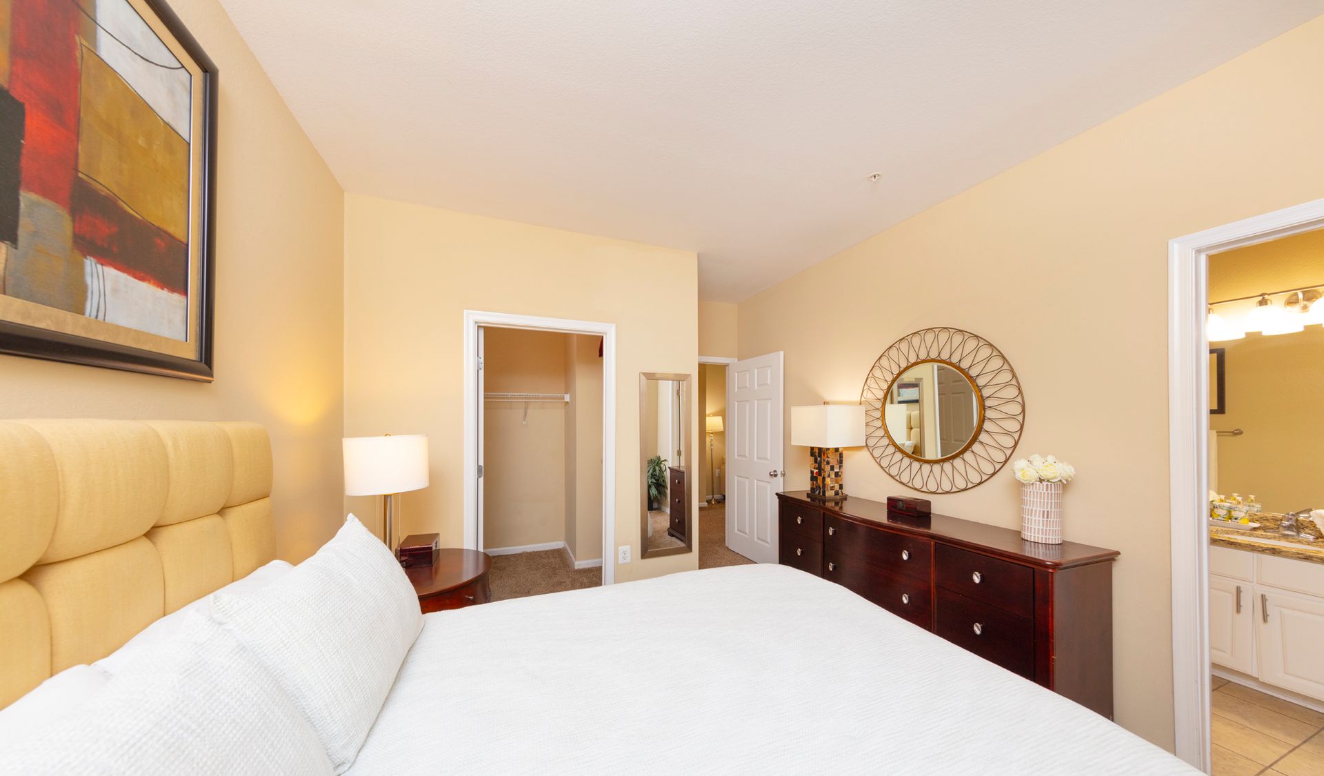 Bedroom with bed, dresser, closet, mirror, and access to the bathroom.