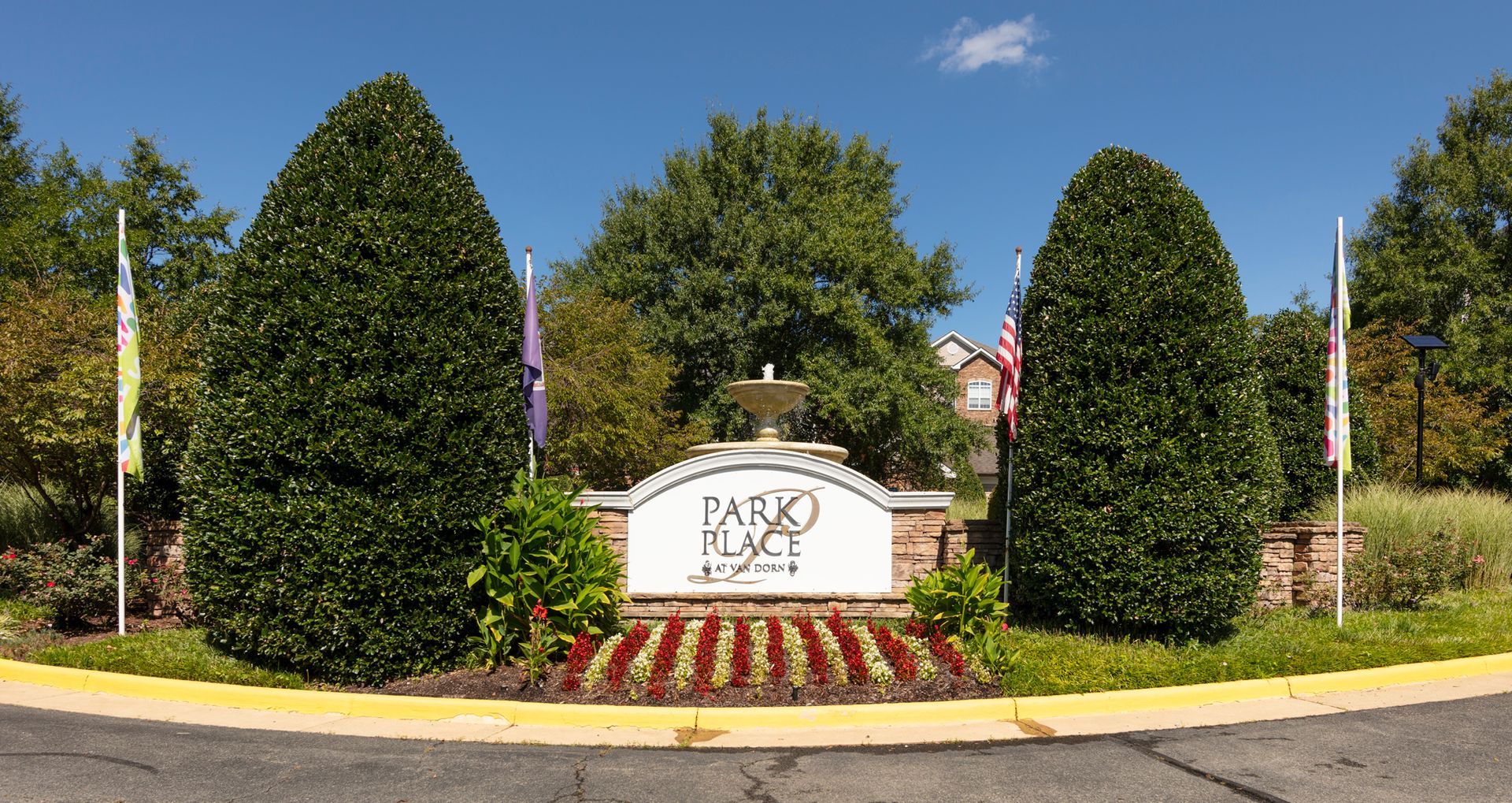 Entrance sign with landscaping and fountain; blue sky.