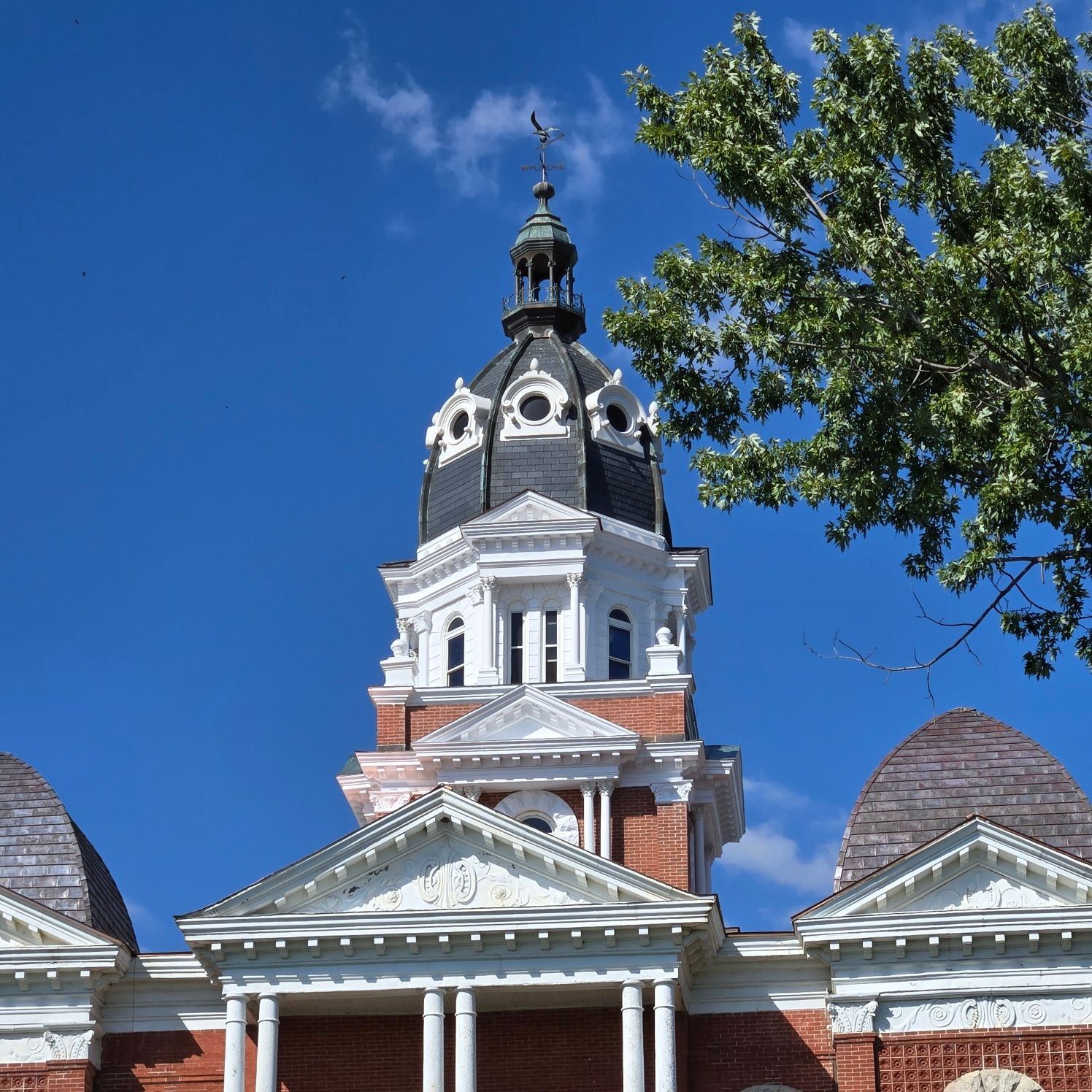 Clock tower with white trim and black dome, against a bright blue sky.