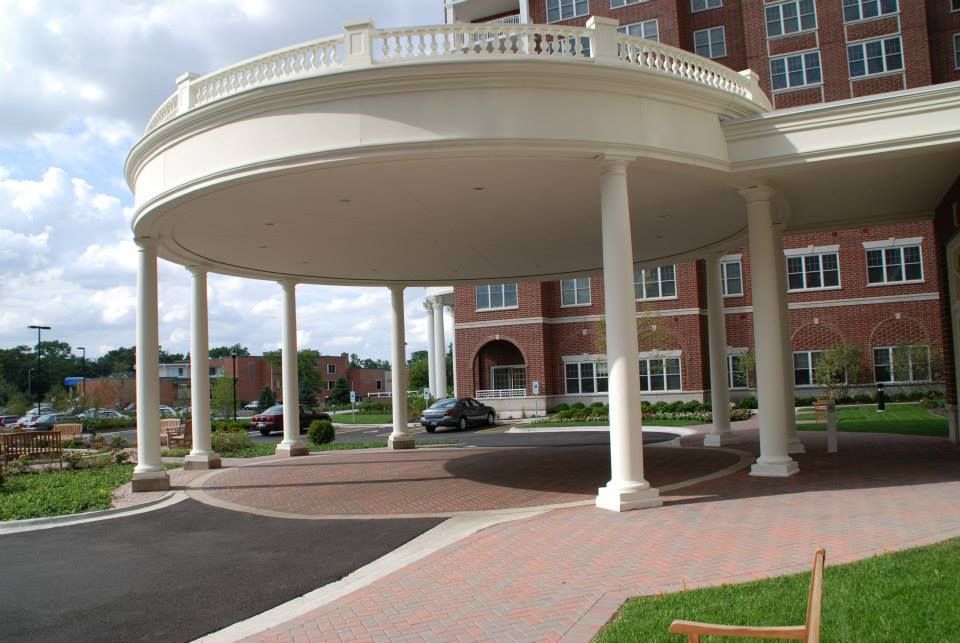 A car is parked under a white canopy in front of a brick building