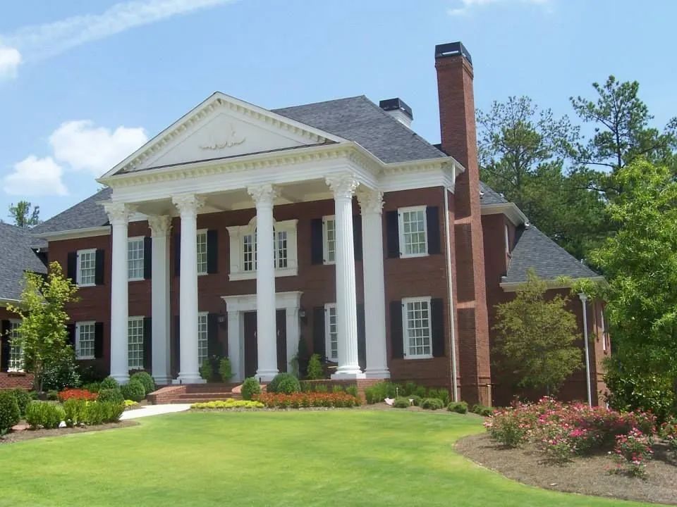A large brick house with white columns and a chimney