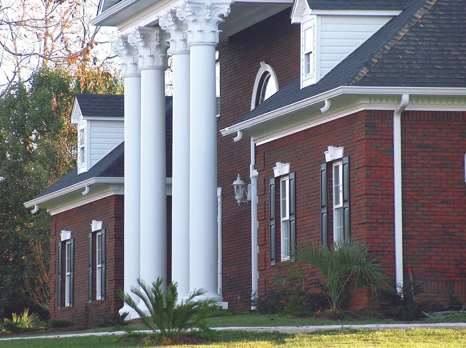Red brick house with white columns and black shutters.