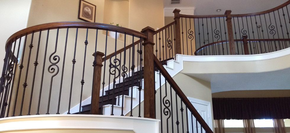 A wooden staircase with a wrought iron railing in a house.