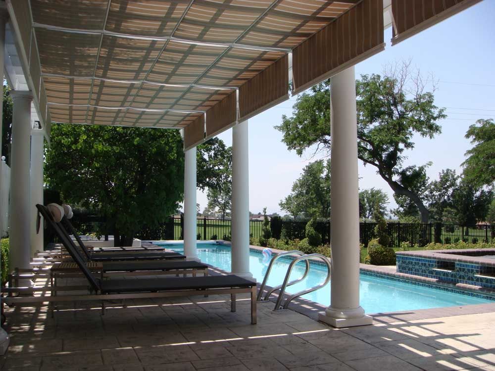 A patio with chairs and a pool under a pergola