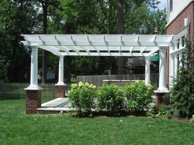 A white pergola is in the backyard of a house